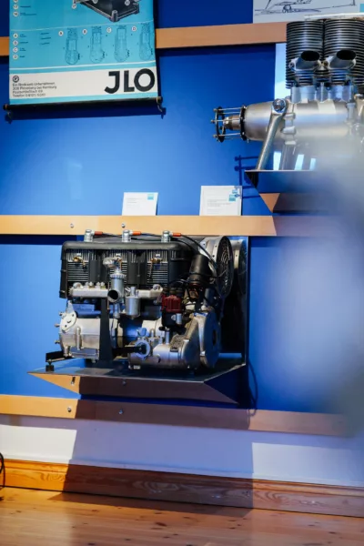 Technische Zeichnungen und Motoren der ILO-Motorenwerke im Ausstellungsraum.